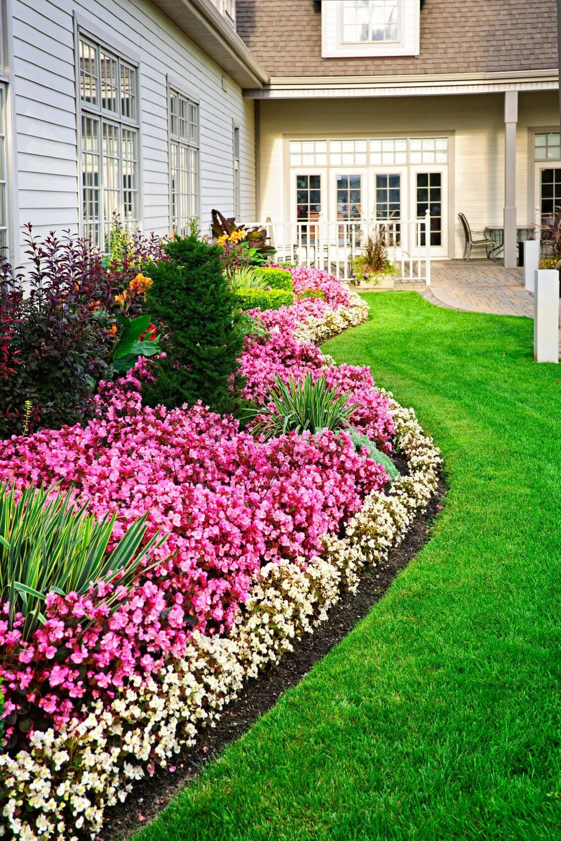Tall view of a layered flower bed running along a light-colored house