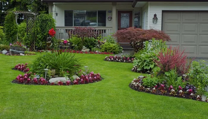 Front yard with a mowed lawn, mulched flower beds, and a house behind them